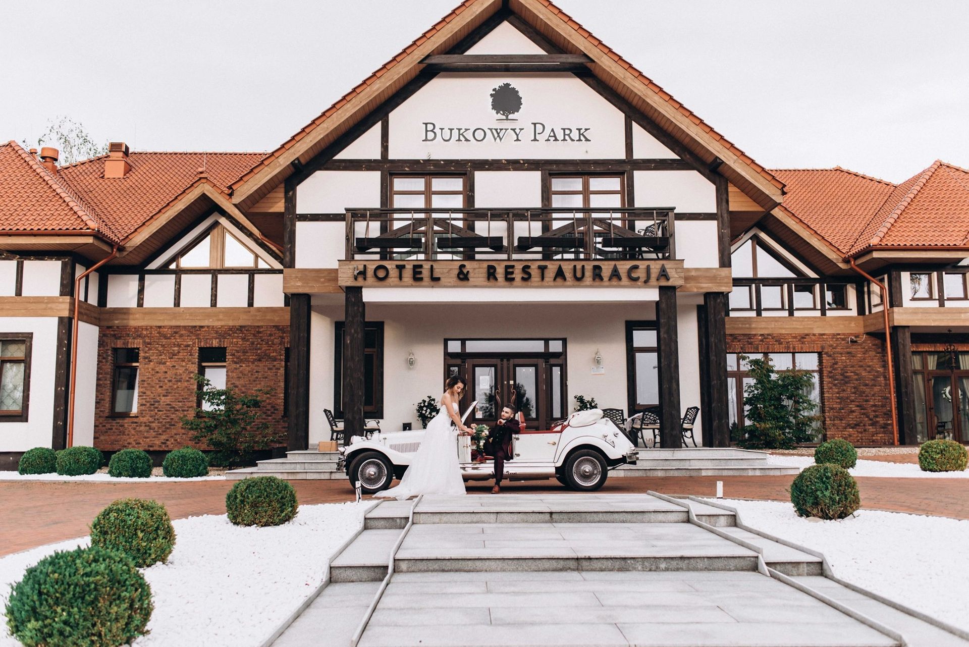 Dworek Bukowy Park z parą młodą i zabytkowym autem przed wejściem